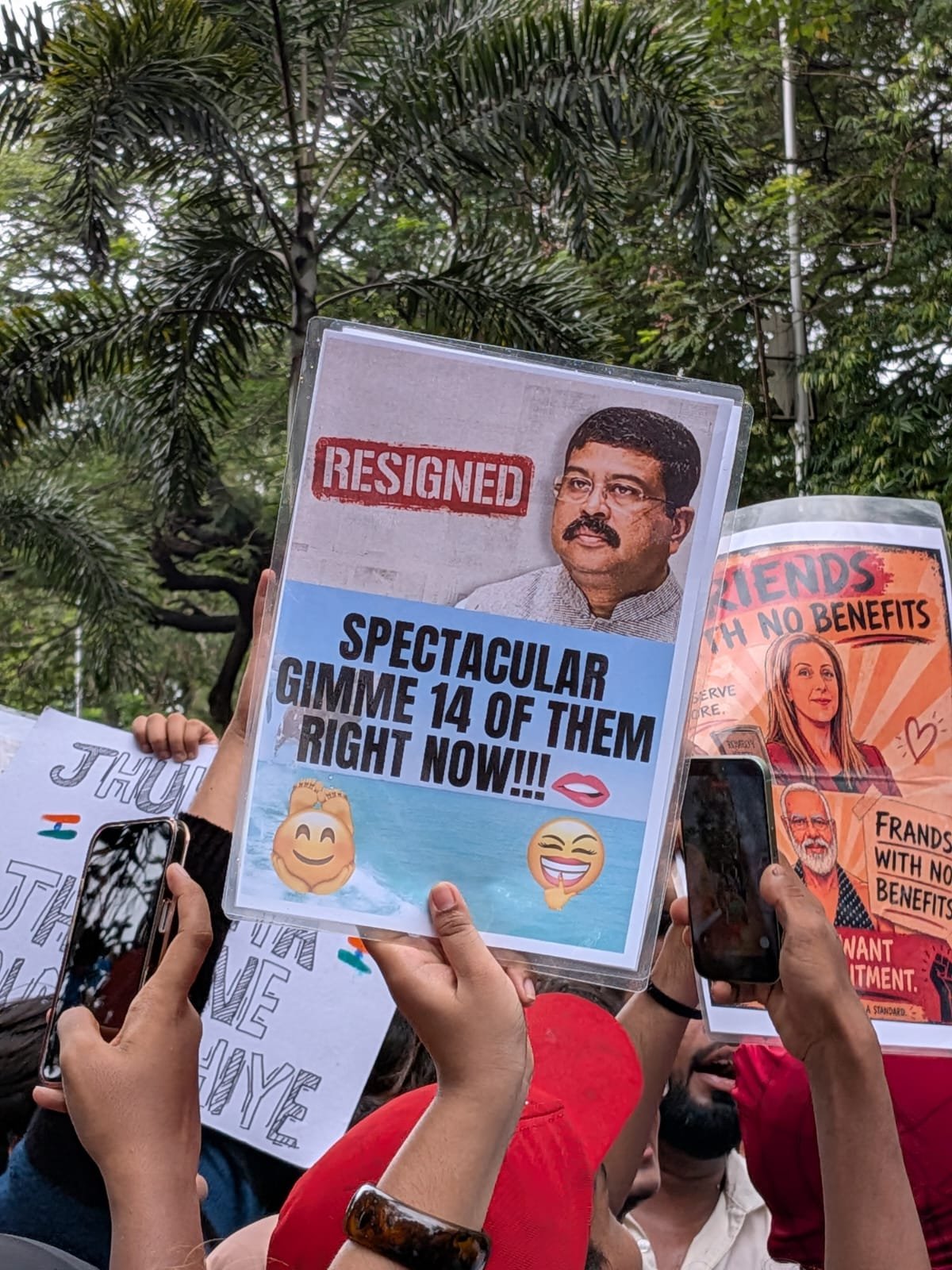 A laminated placard stamps RESIGNED across the minister's portrait and demands: spectacular, gimme 14 of them right now