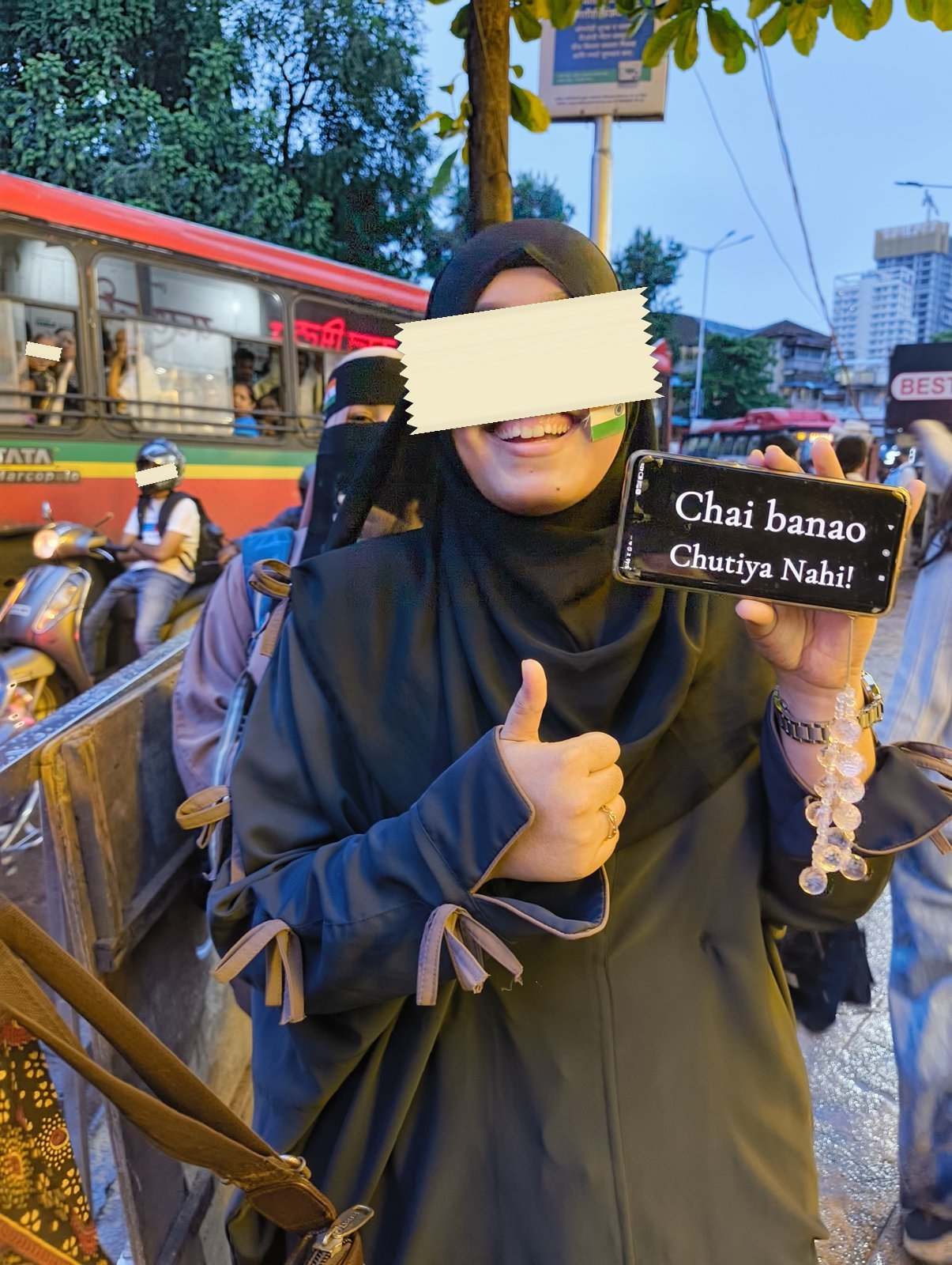 A smiling protester with a tricolor sticker on her cheek holds up a phone reading Chai banao, chutiya nahi