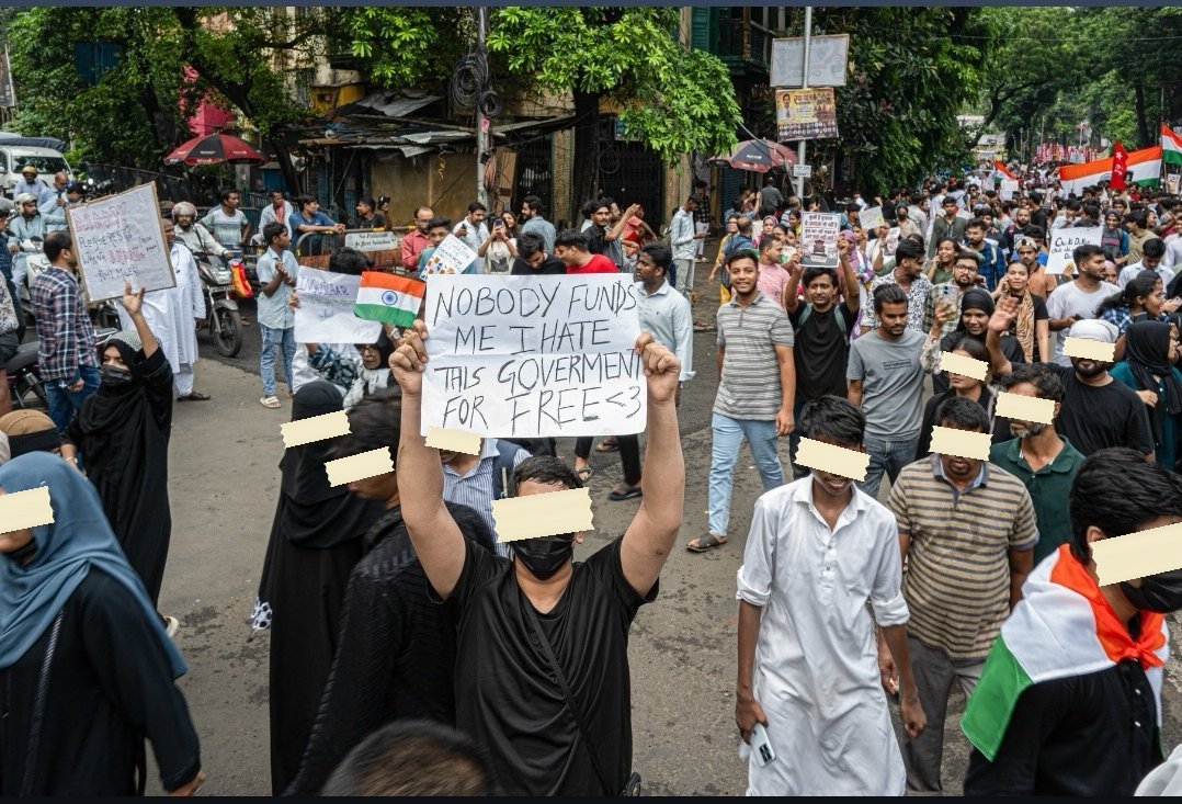 Marchers fill a Kolkata street, one holding a sign reading Nobody funds me, I hate this government for free