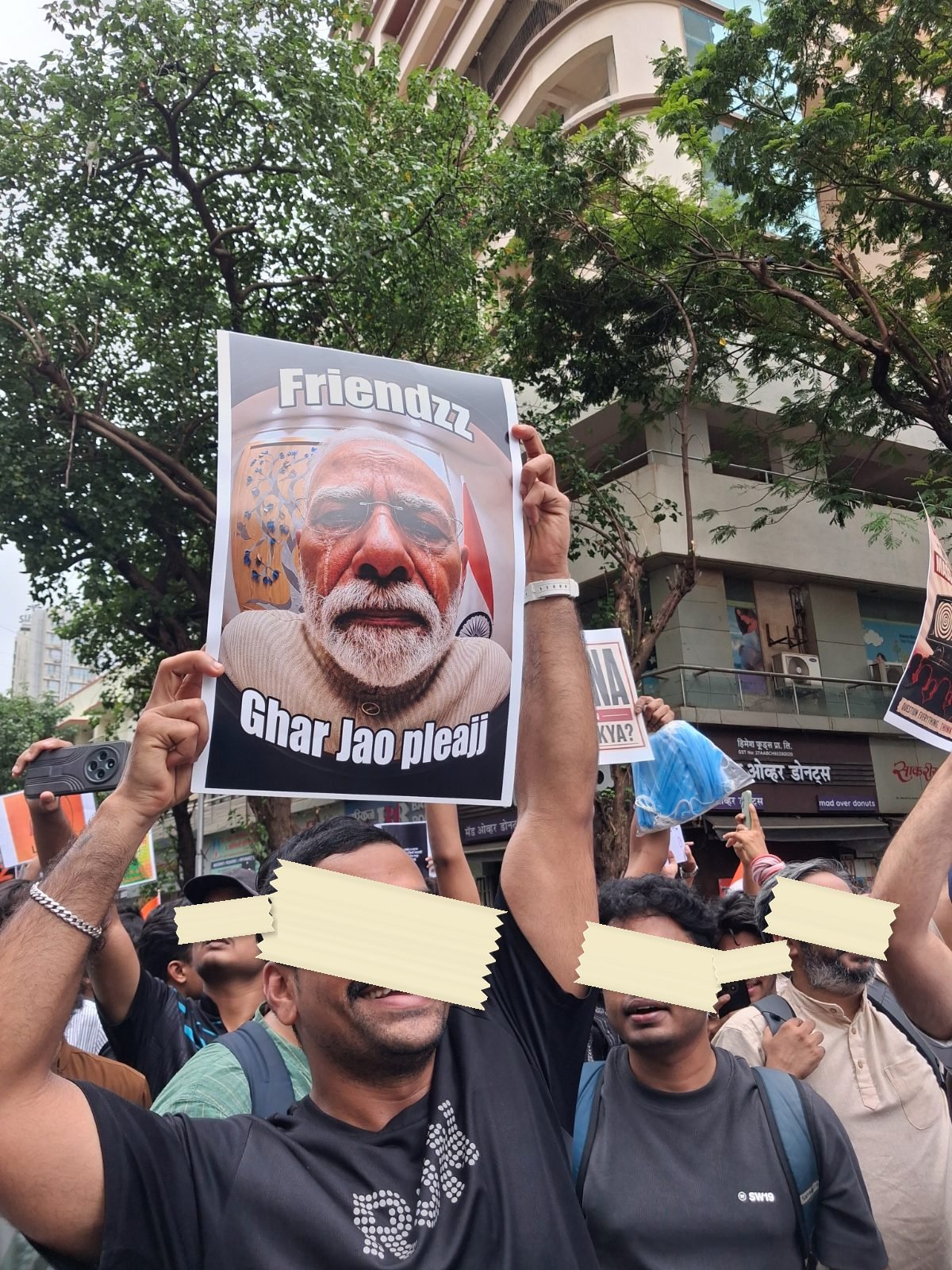 A poster held above a Mumbai march reading Friendzz above a portrait of the Prime Minister and Ghar Jao pleajj below