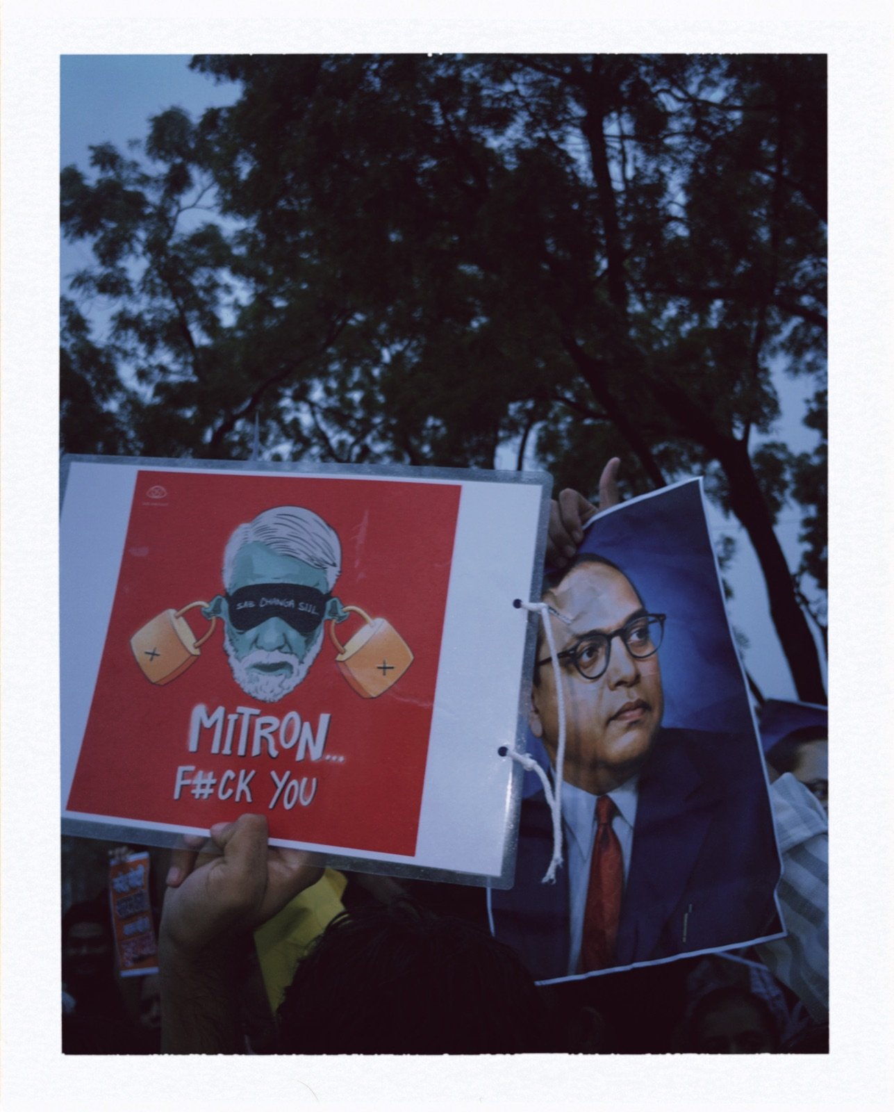 A red caricature poster of the Prime Minister held up beside a printed portrait of B.R. Ambedkar
