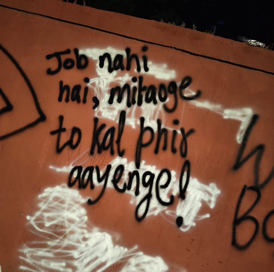 Graffiti sprayed across a patch of white paint covering earlier writing