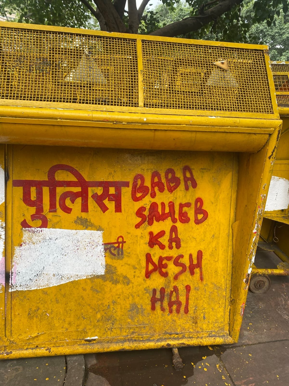 A police barricade painted with the word police in Devanagari and the words Baba Saheb ka desh hai