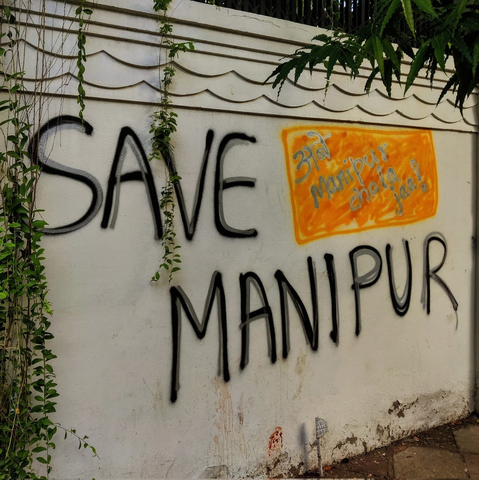 The words Save Manipur painted in large letters on a white boundary wall