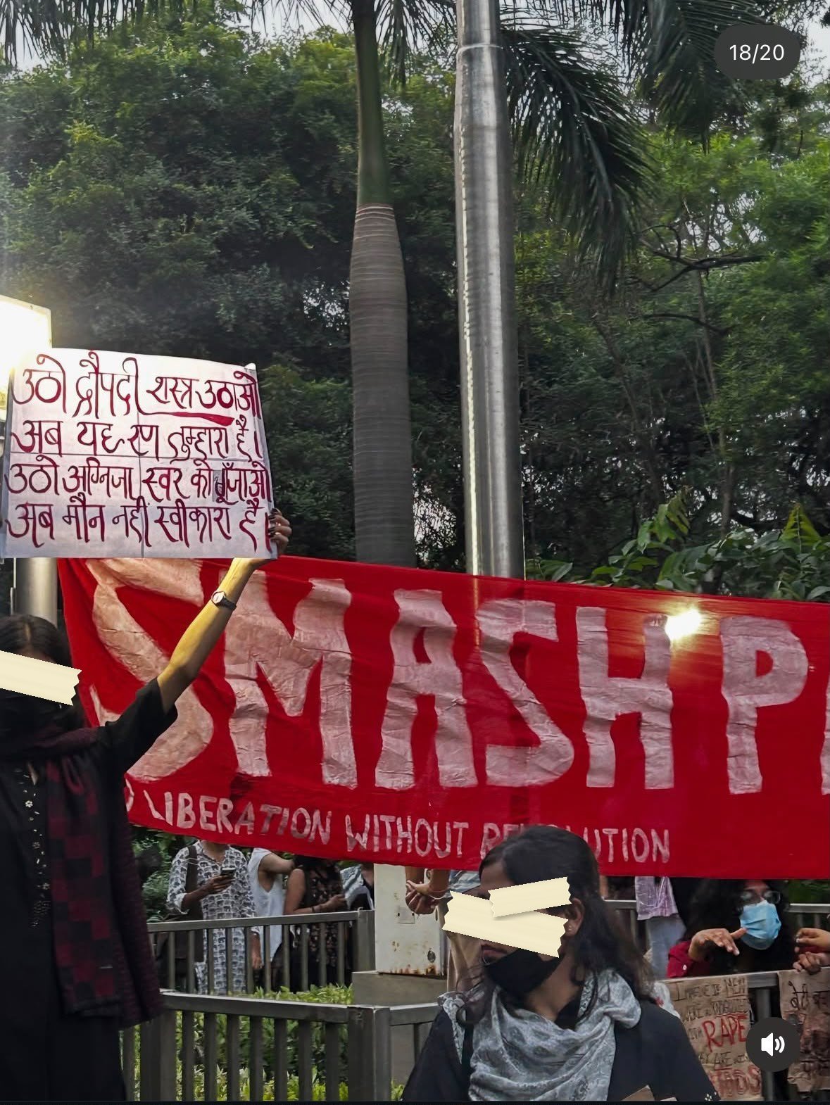 A hand-lettered placard in red Devanagari held above a large red banner reading SMASH PATRIARCHY, NO LIBERATION WITHOUT REVOLUTION.