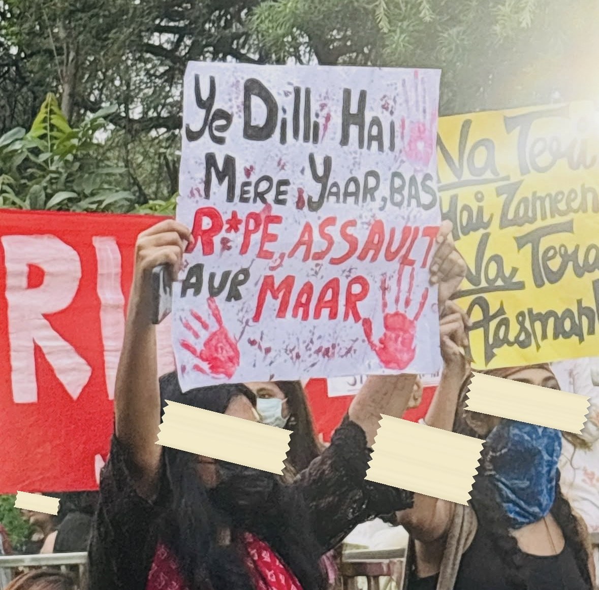 A hand-lettered placard reading Ye Dilli Hai Mere Yaar, Bas RAPE, ASSAULT AUR MAAR with a red handprint, held in a crowd beside a red banner.
