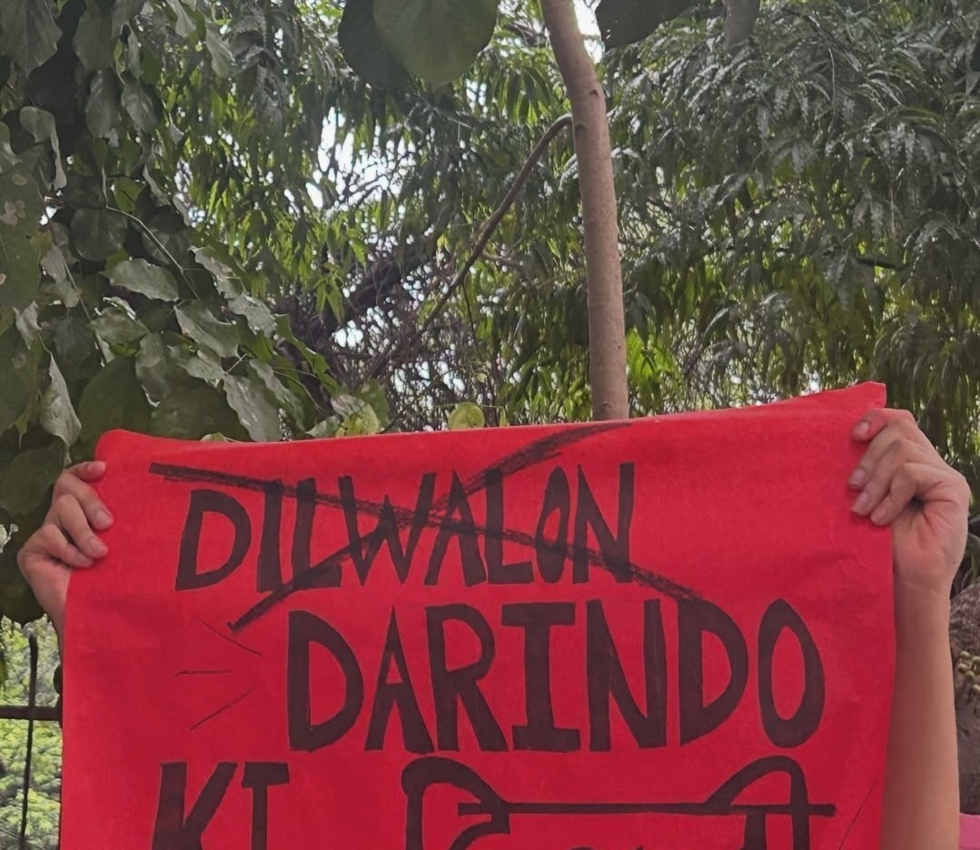 A red placard with DILWALON struck through in a single diagonal line and DARINDO KI written beneath it, ending in the Hindi word Dilli.
