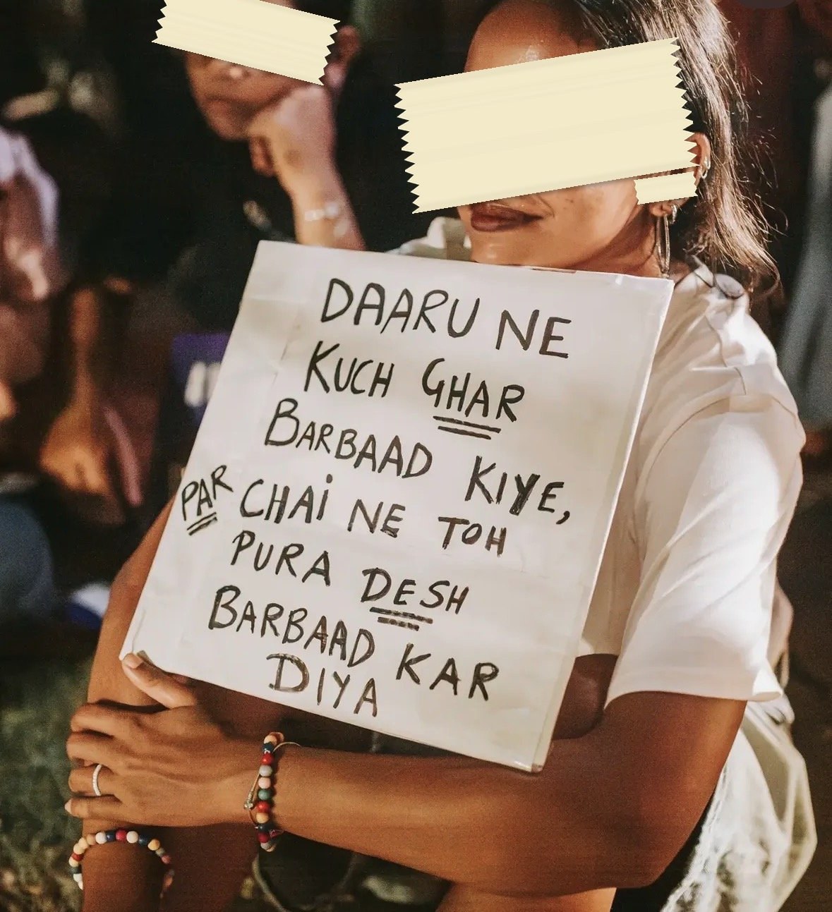 A hand-lettered placard in Hindi written in Roman script: daaru ne kuch ghar barbaad kiye, par chai ne toh pura desh barbaad kar diya.