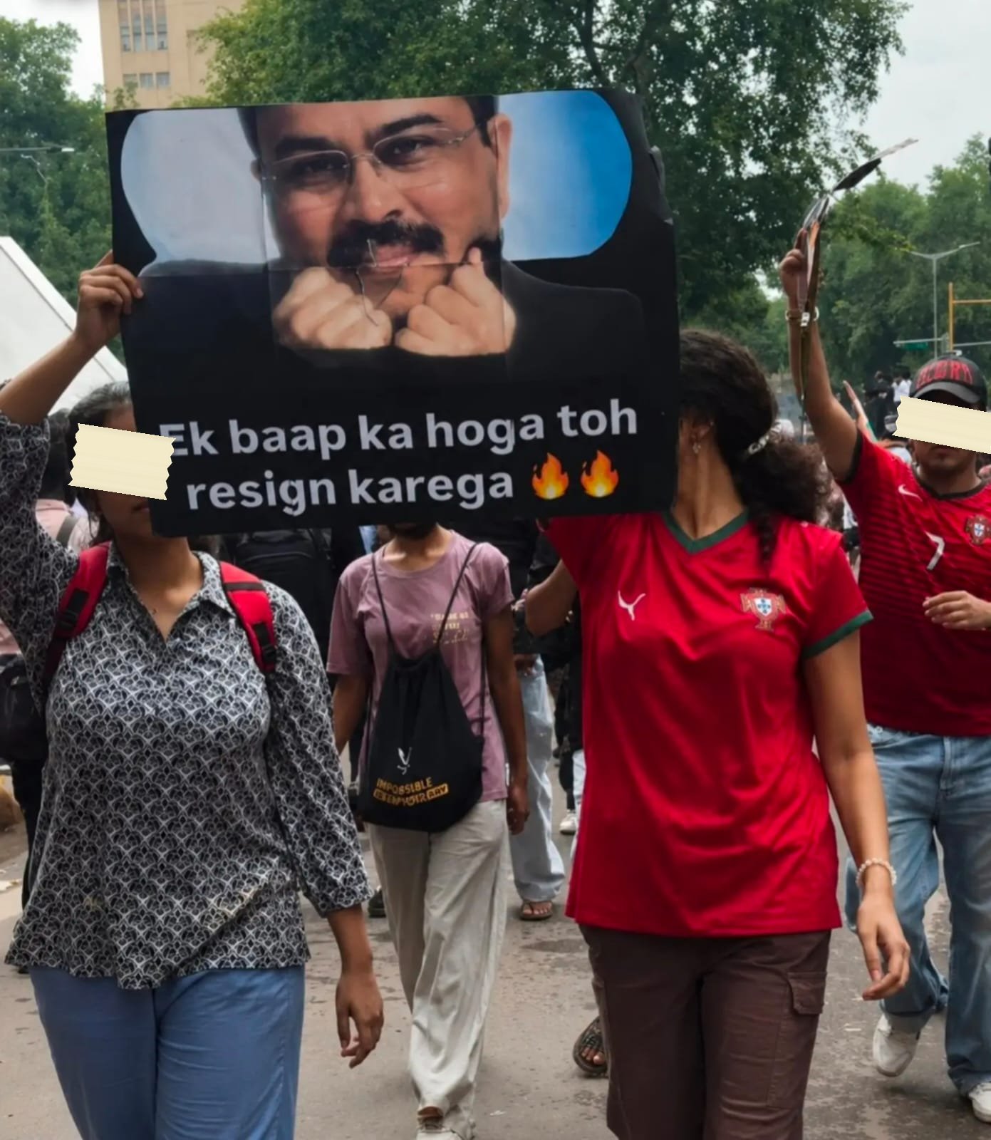 A poster of the education minister carried through a march, captioned in Hindi