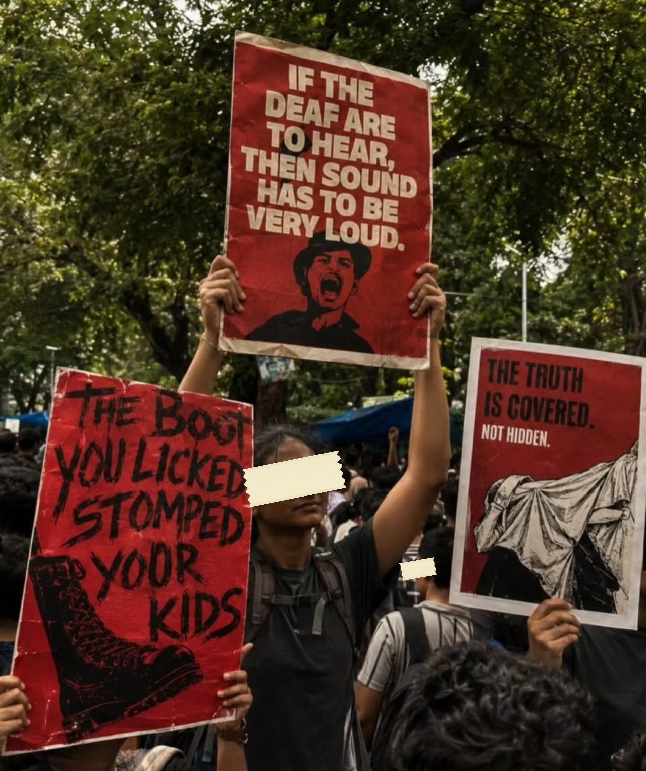 Three red screen-printed placards raised together: If the deaf are to hear then sound has to be very loud, The boot you licked stomped yoor kids, and The truth is covered not hidden