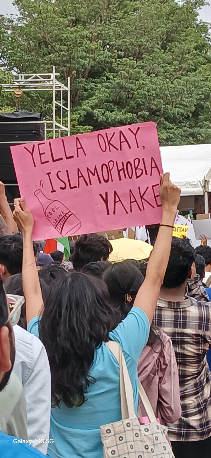 A pink placard in Bengaluru reading Yella okay, Islamophobia yaake, with a drawing of a bottle