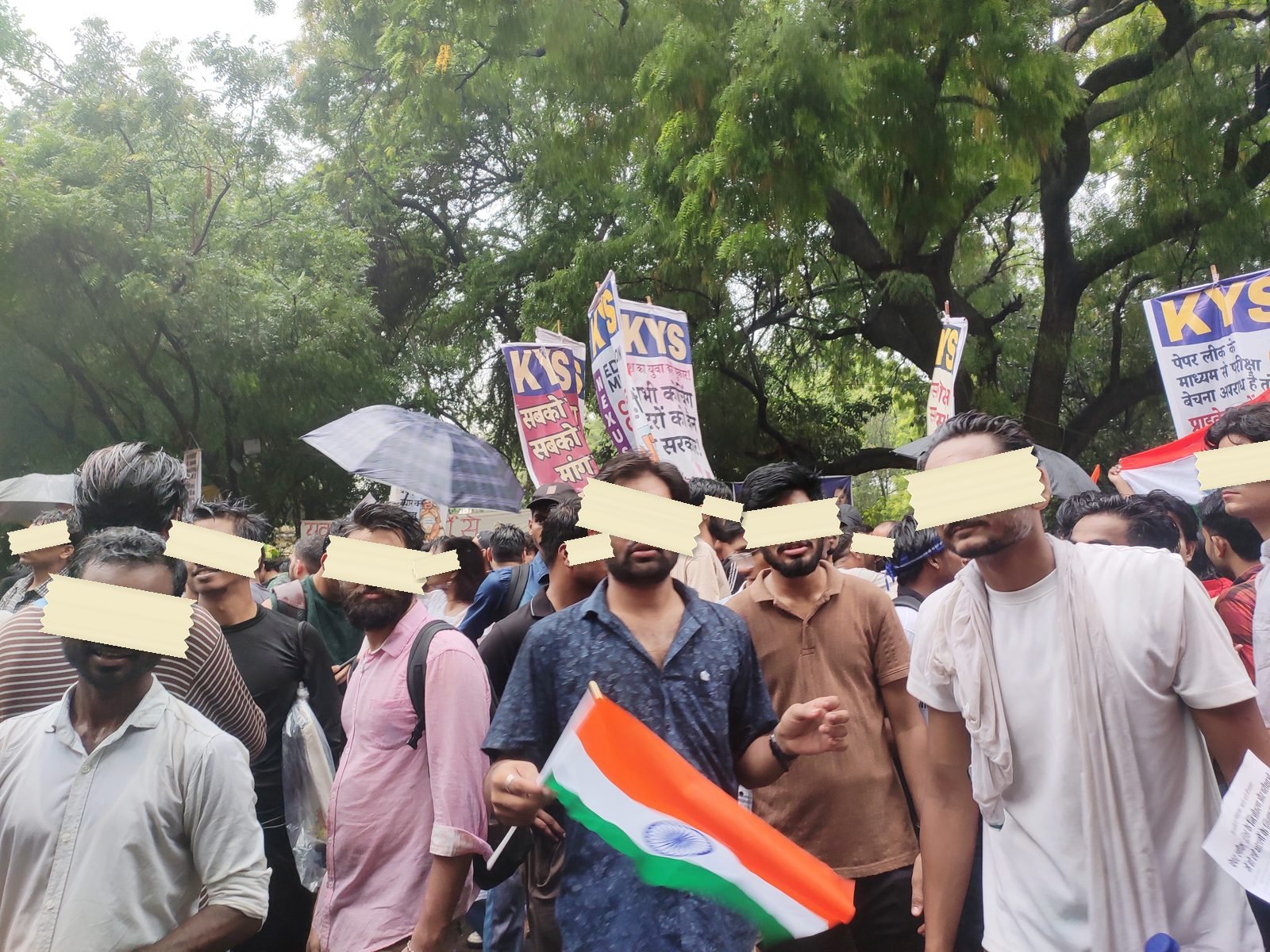 Marchers with union placards and a tricolor move under umbrellas in the rain