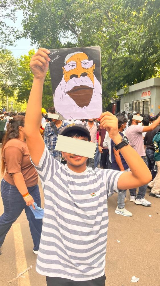 A protester in Ranchi holding a hand-lettered Hindi placard saying his girlfriend's father will not agree, so give him a job.